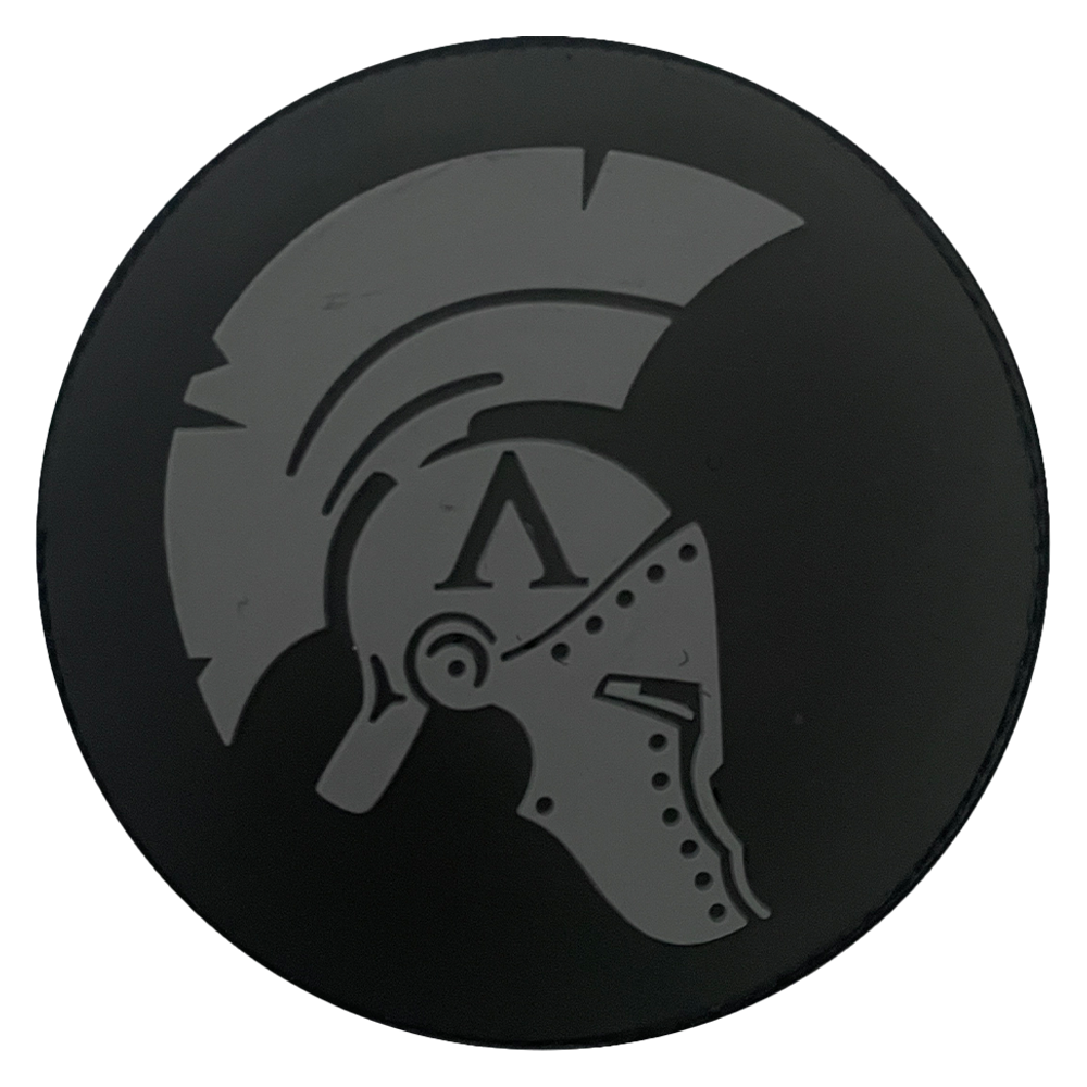 Black circular PVC patch with a gray Spartan Achilles helmet design on a plain white background