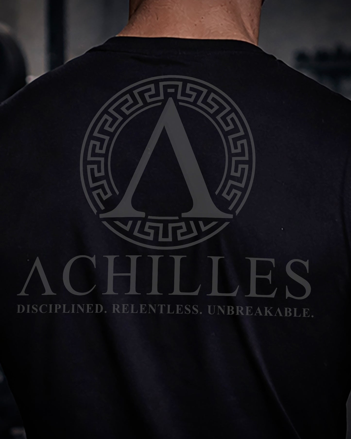 Close up of back view of man wearing black Achilles T-shirt printed with full sigil logo on back