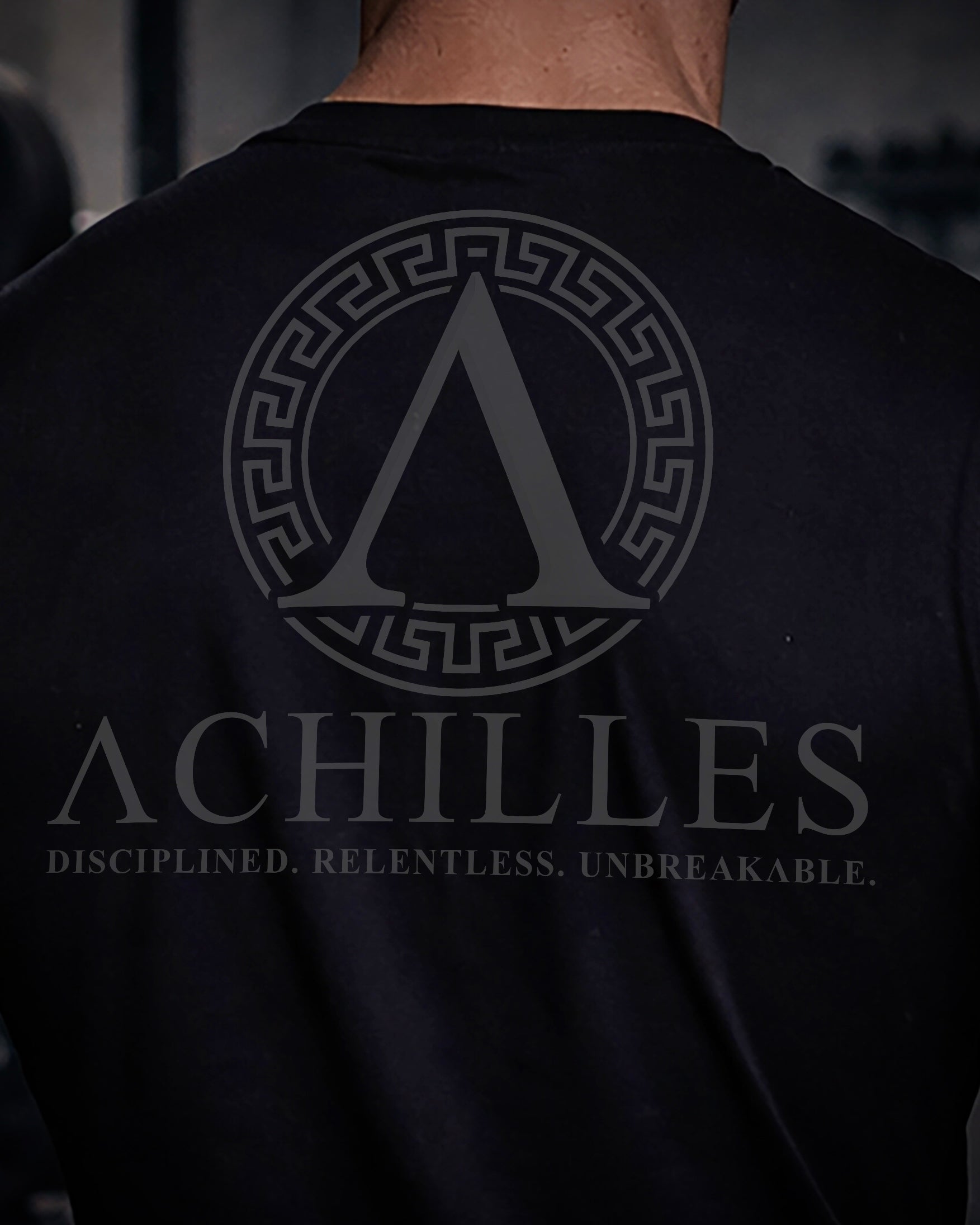 Close up of back view of man wearing black Achilles T-shirt printed with full sigil logo on back