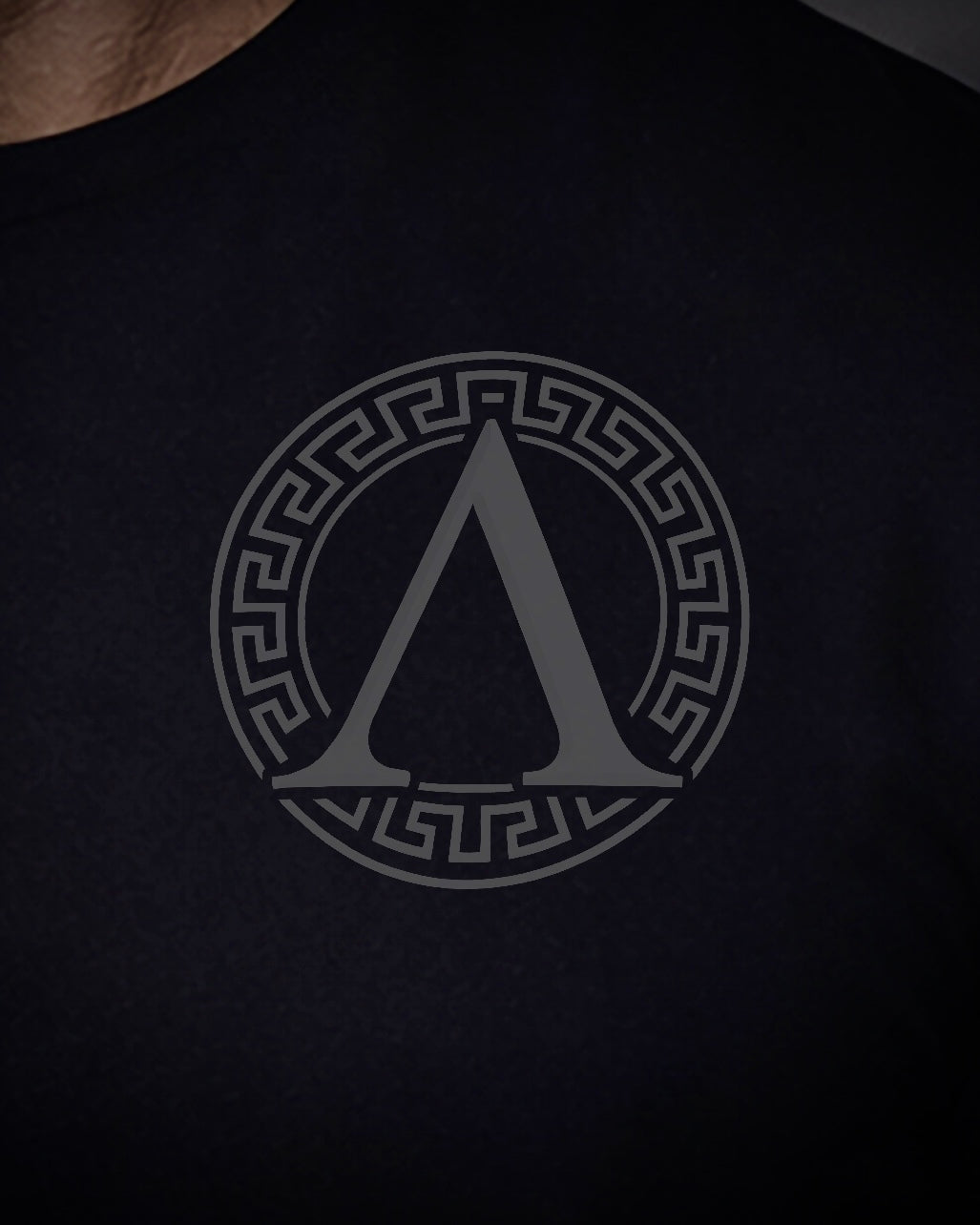 Close up of front view of man wearing black Achilles T-shirt printed with roundel logo on chest
