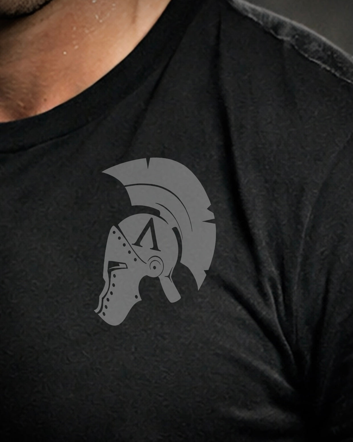 Close up front view of man wearing black Achilles T-shirt printed with Original Achilles logo on chest