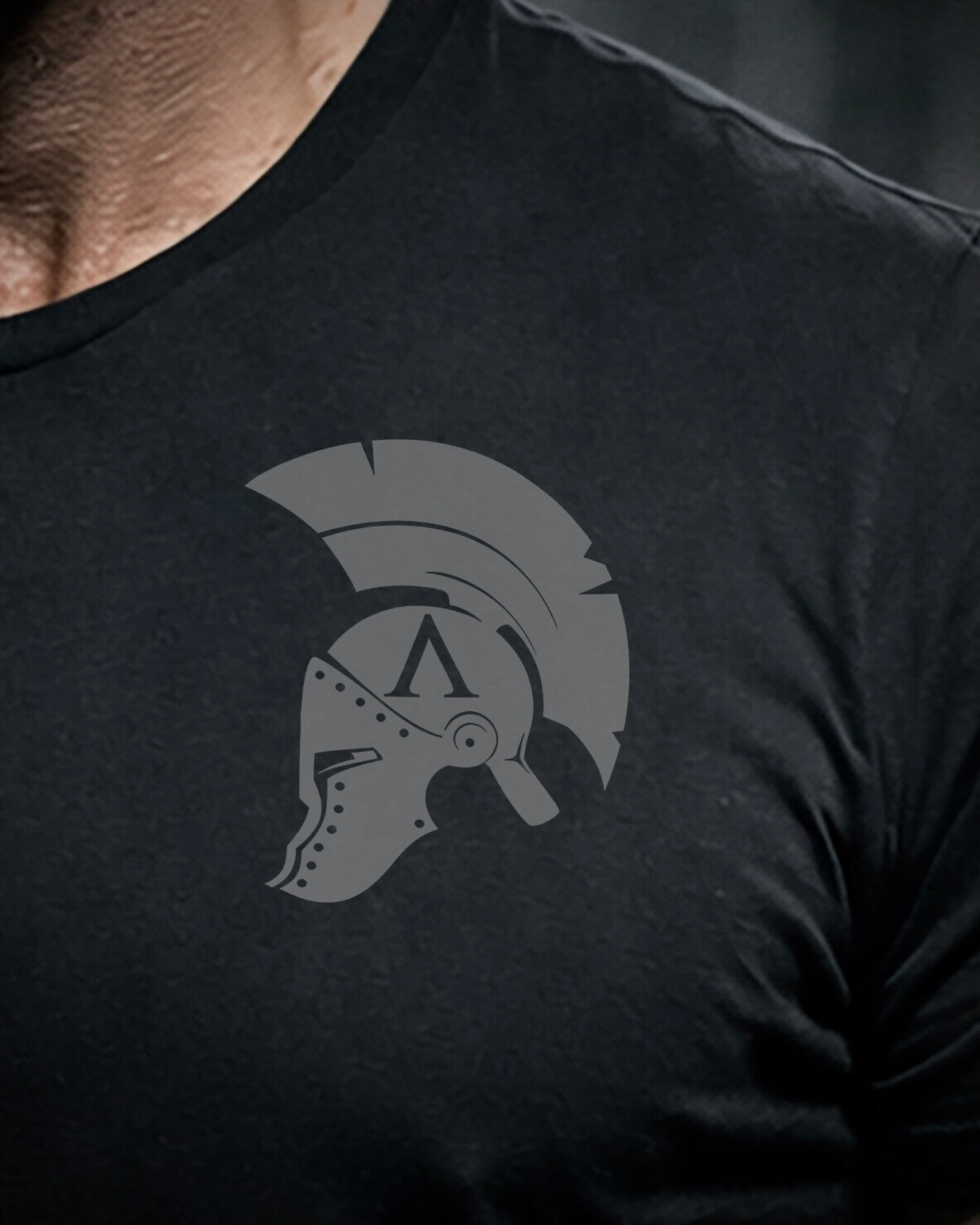 Close up of front view of man wearing black Achilles T-shirt printed with Achilles helmet design on chest