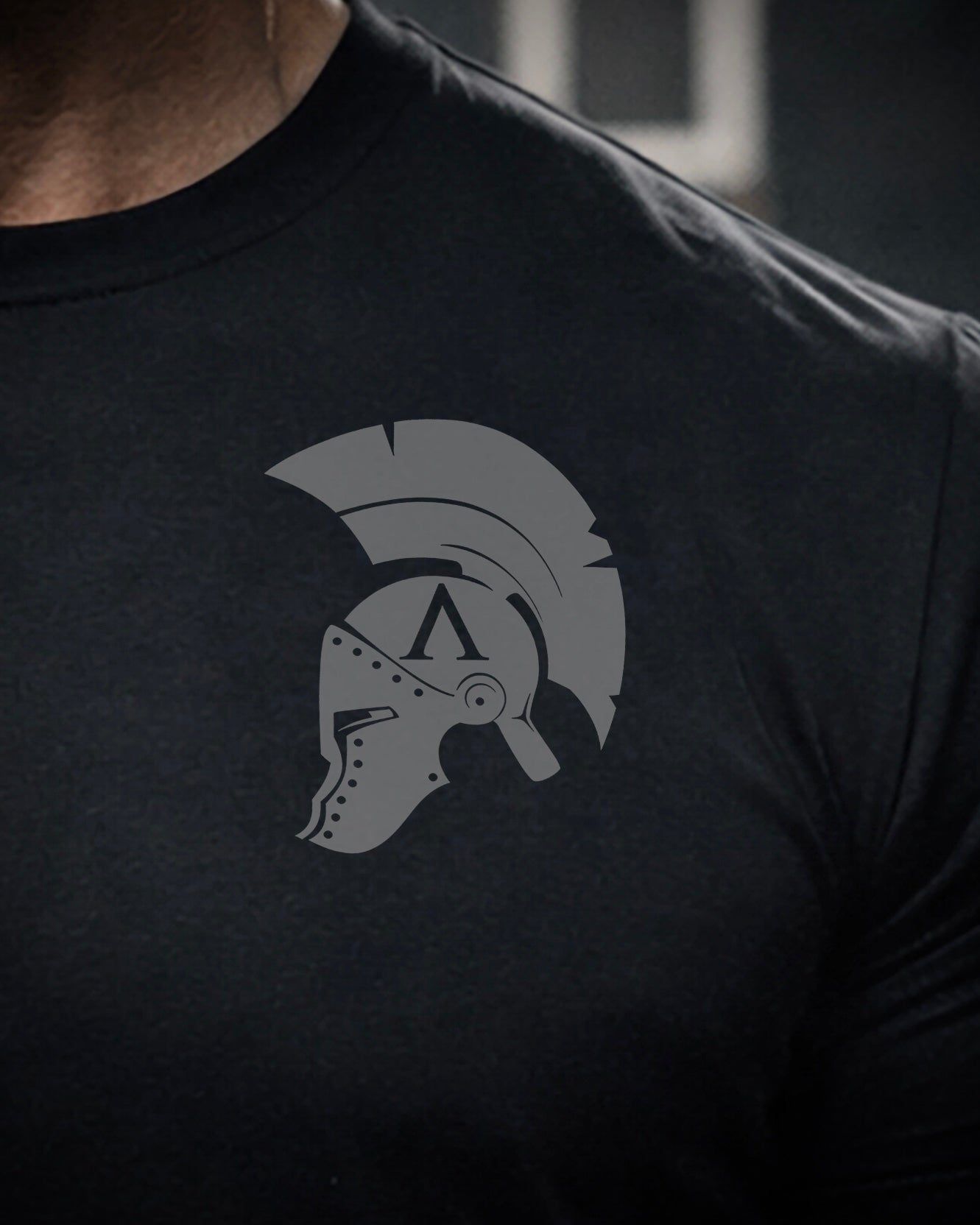 Close up of front view of man wearing black Achilles T-shirt printed with original achilles Spartan helmet on chest