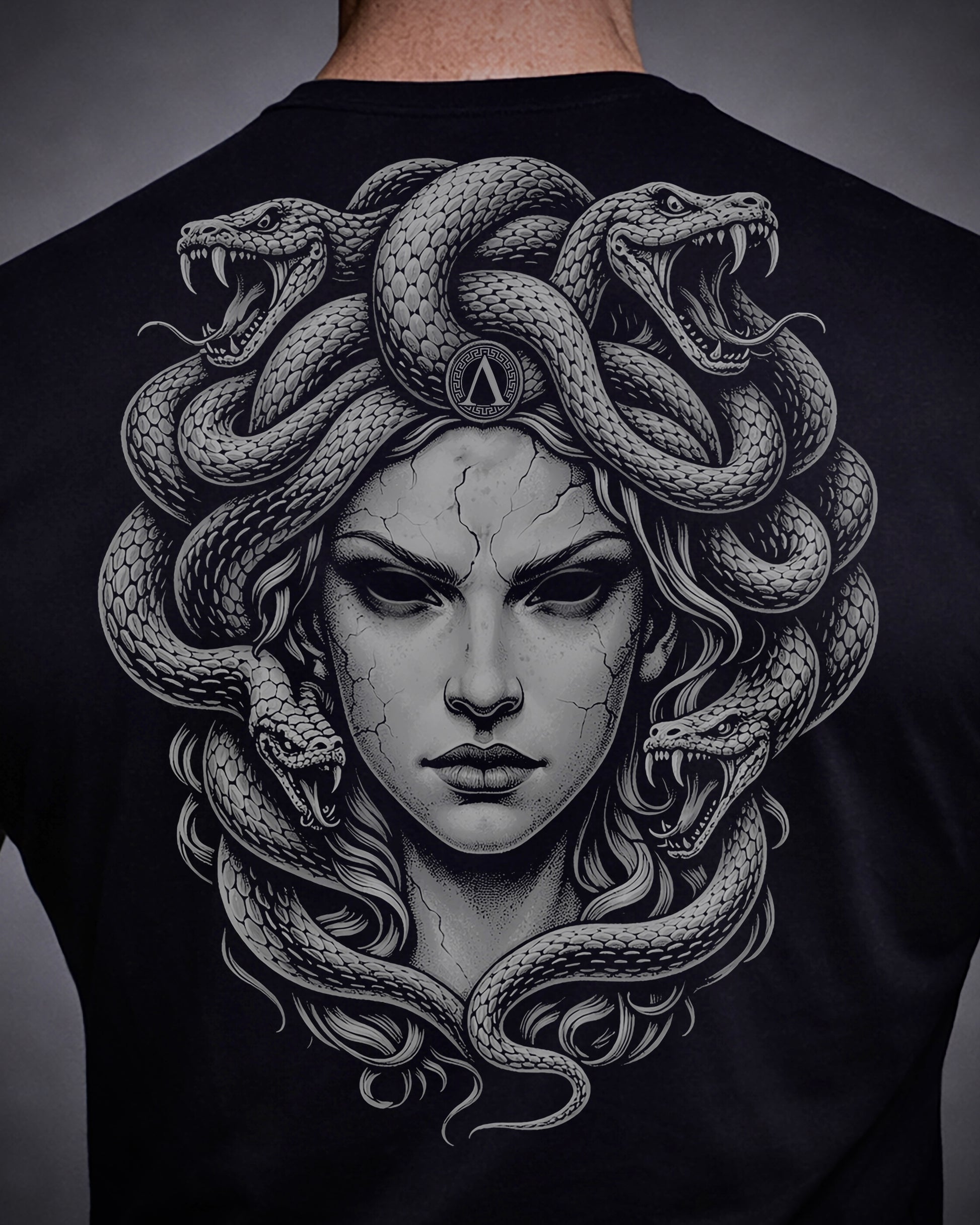 Close up of back view of man wearing black Achilles T-shirt printed with large Medusa logo on back