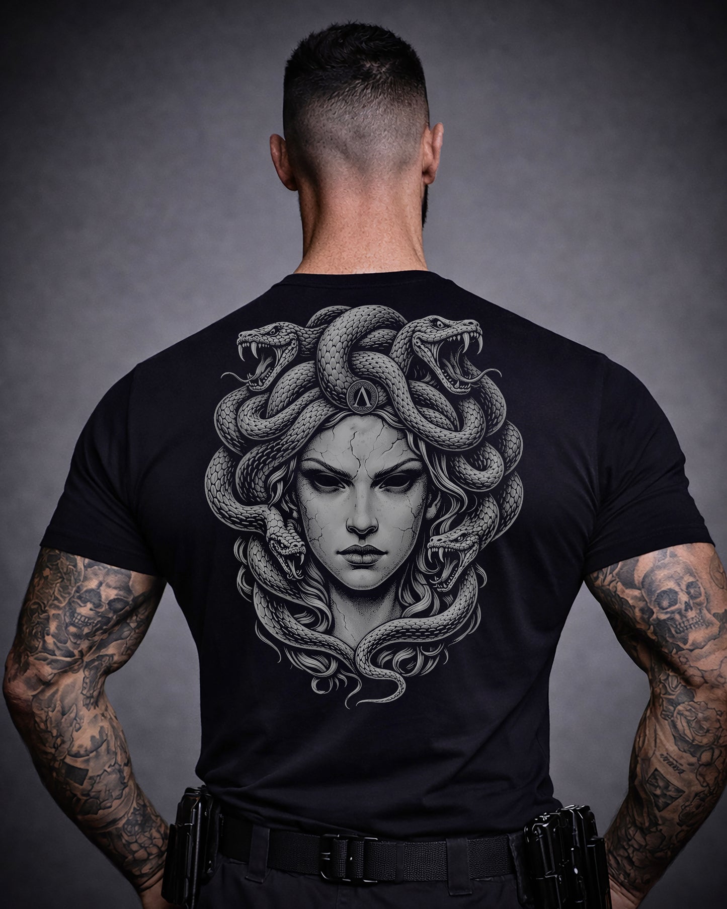 Back view of man wearing black Achilles T-shirt printed with large Medusa logo on back