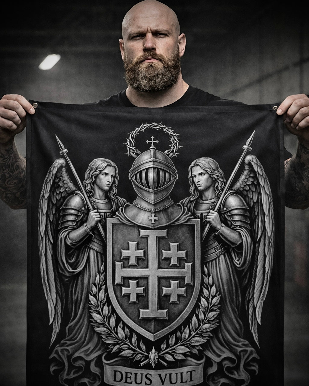 Man holding a black banner with a central coat of arms featuring two angels and the text 'Deus Vult'.