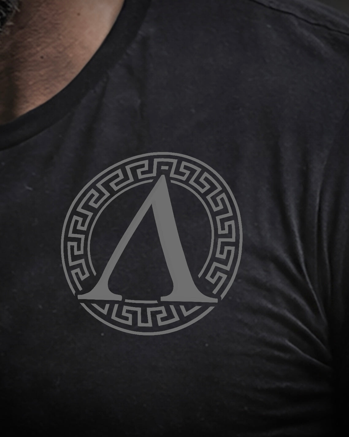 Close up of front view of man wearing black Achilles T-shirt printed with Roundel logo on chest